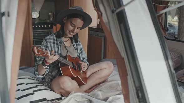 Happy Woman Playing Song on Ukulele in Camper