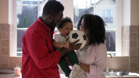 Medium Shot Excited Little African American Boy with Soccer Ball and Happy Couple of Parents Smiling