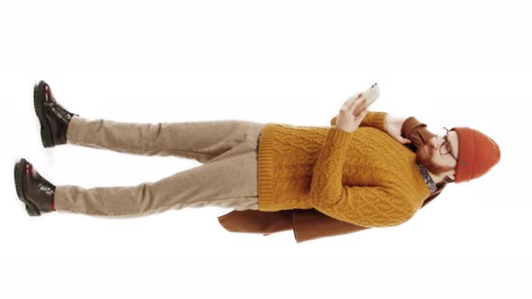 Vertical Studio Shot of a Caucasian Man Wearing Yellow Sweater and a Beanie Looking at His