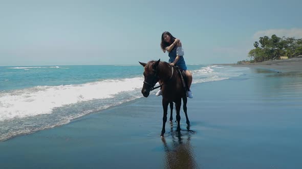 Cute Chinese Teenager Rides a Horse On The Beach In Bali