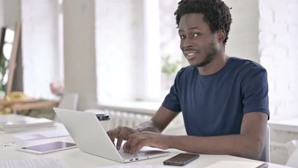 Young African Man Showing Thumbs Up at Work