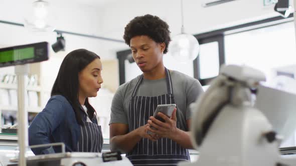 Animation of serious diverse female and male waiters using tablet at coffee shop and talking