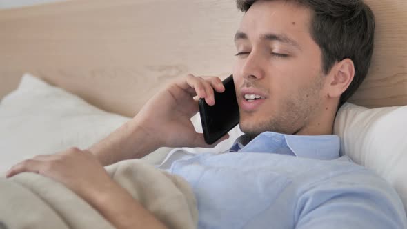 Relaxing Young Man Talking on Phone in Bed