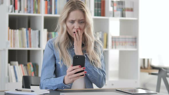 Blonde Woman in Shock while Using Smartphone