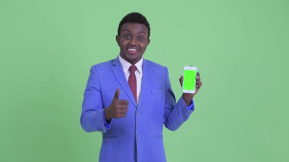 Happy Young African Businessman Showing Phone and Giving Thumbs Up