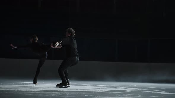 Slow Motion Young Couple of Artistic Figure Skaters is Performing a Pair Skating Choreography on Ice