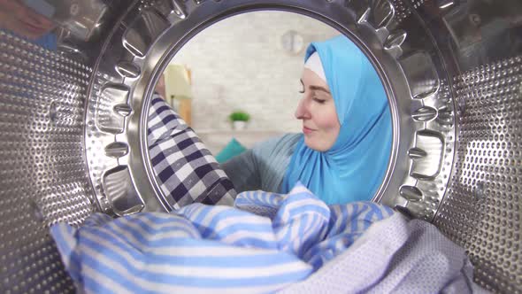 Young Muslim Woman Takes Clean Laundry Out Washing Machine