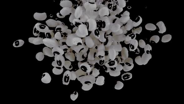 Super slow motion, a heap of cowpeas  fall into the water with air bubbles on a black background.