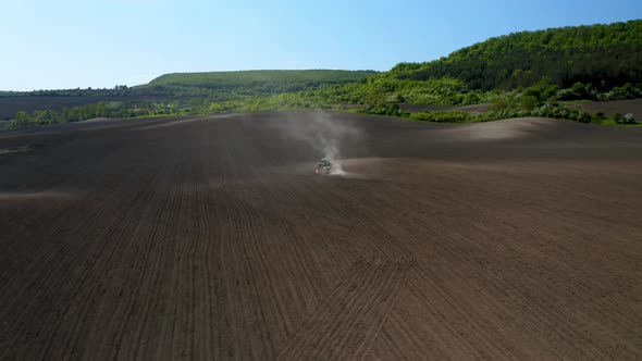 Field with picturesque hills and a moving tractor