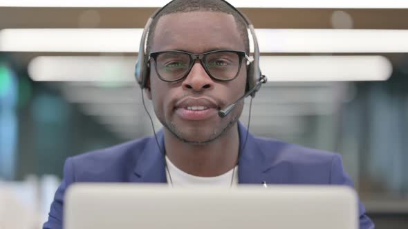 Portrait of Smiling African Businessman with Headset Working on Laptop