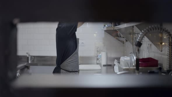 Male Chef Working in Restaurant Kitchen Seen Through Hole in Wall