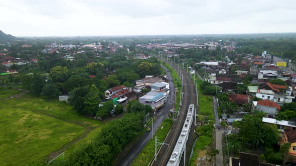 Aerial tracking shot of electric train rides across Yogyakarta city, Indonesia