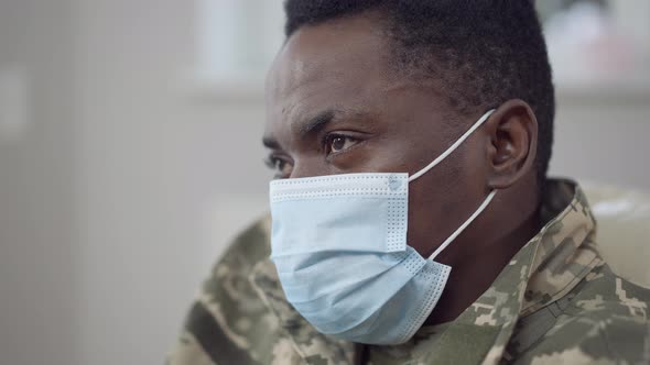 Closeup Face of Sad African American Man in Coronavirus Face Mask Looking Away Thinking Indoors