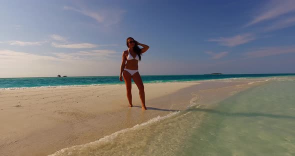 Modern happy lady on vacation having fun at the beach on summer white sandy and blue 4K background