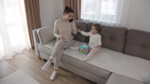 Mother Working From Home Having a Work Video Call Daughter Playing Nearby