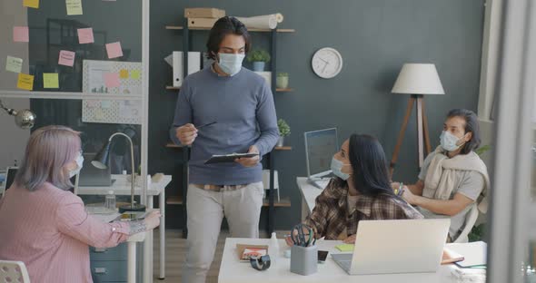 Boss Arab Guy Talking to Diverse Group of People Employees Wearing Medical Masks in Office