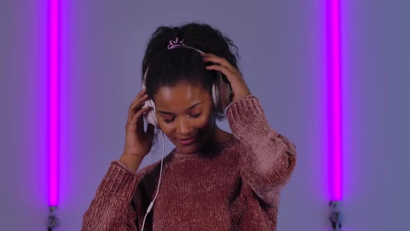 Portrait of Afro American Young Woman Dancing and Enjoying Music in Big White Headphones