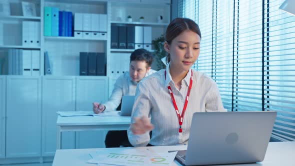 Asian attractive business people use laptop computer overworking late in office workplace.