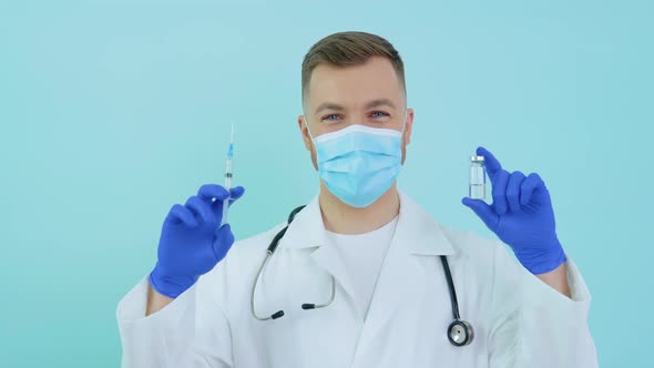 Doctor Holds an Ampoule with a Vaccine and a Syringe in His Hands on a Blue Background