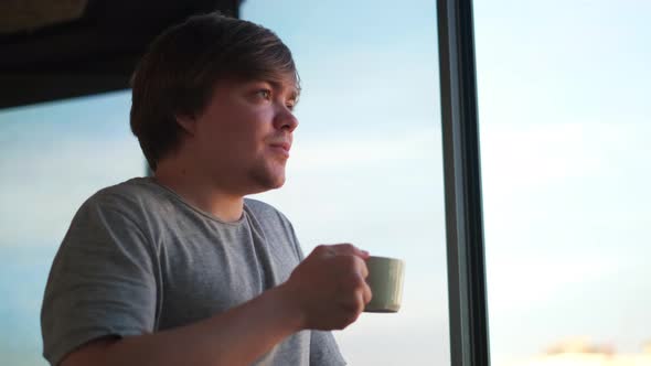 Happy man at home balcony relaxed and cheerful enjoying cup of coffee