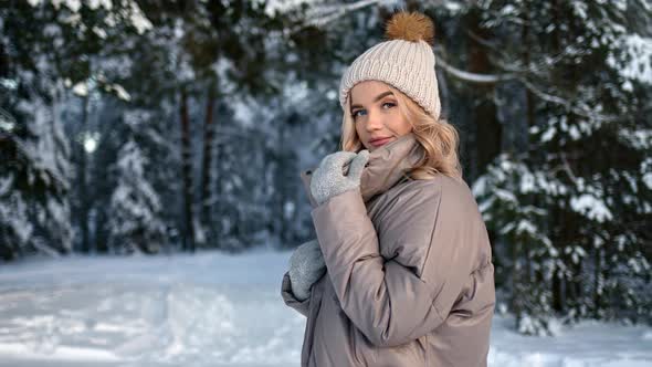 Happy Female in Hat Warm Jacket and Mittens Posing at Winter Forest