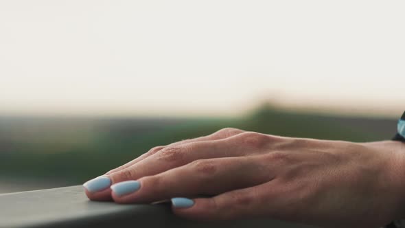 Hand of Young Woman with Blue Nail Runs Over Metal Railing