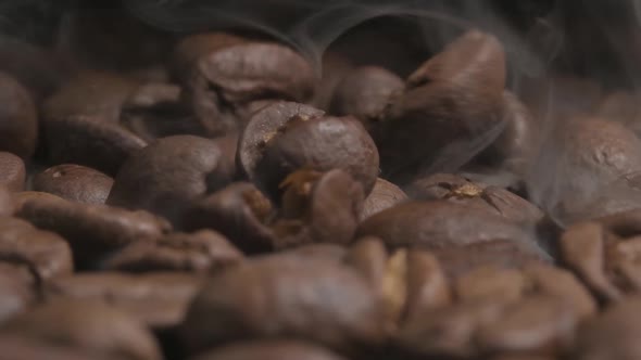 Slow motion macro shot of smoking hot organic coffee beans, dropping onto a cooling tray after roast
