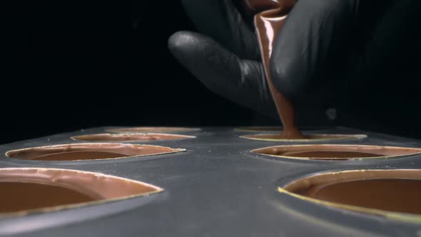 Chocolatier Fills Chocolate Molds with Liquid Chocolate Filling for Praline Sweets