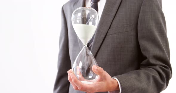 Businessman holding sandglass against white background