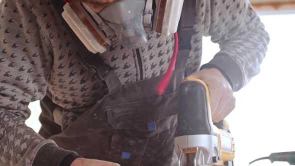 Male Caucasian Worker Wearing Respirator Using Jigsaw for Cutting Plywood in Slowmotion