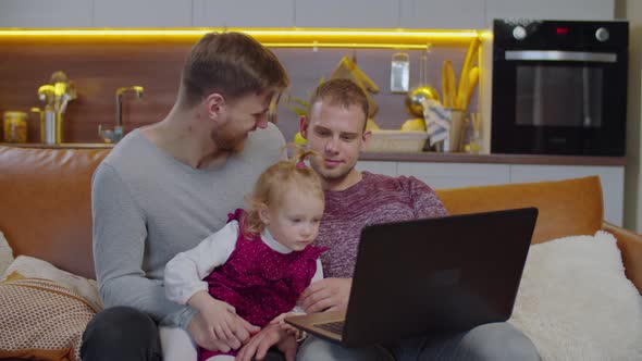 Child with Gay Parents Networking on Laptop on Sofa