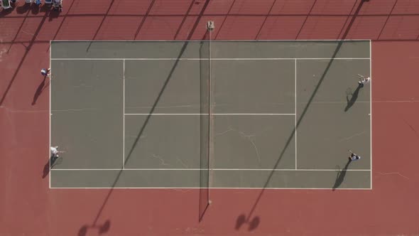 Tennis players enjoying a tennis match on the beach, with sand covering the court corner.