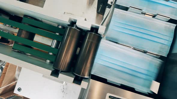 Face Masks Being Automatically Loaded Onto a Conveyor Belt