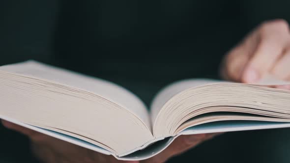 Young Man Reading a Book and Turning Pages Close Up Slow Motion