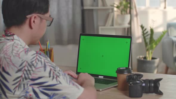 Photographer, Videographer Works On His Laptop Computer With Green Screen Display