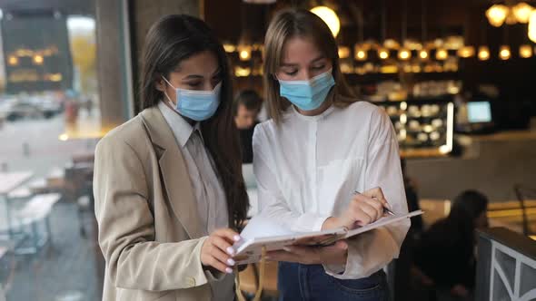 Two Businesswomen with Their Face Masks Debating Different Views on Work