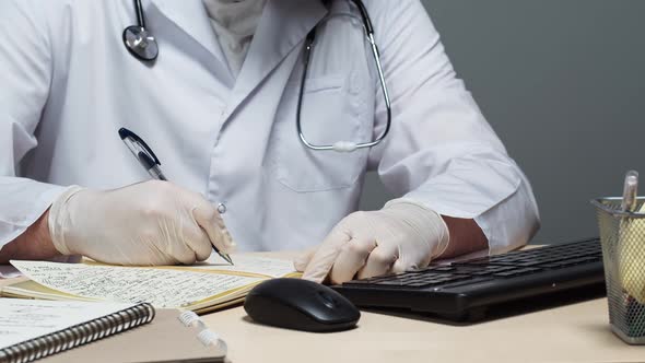 Man Doctor Wearing Protective Gloves Medical Gown Sitting and Writing Documents Closeup Typing on