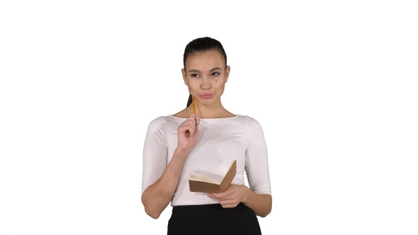 Young woman making notes while walking on white background.