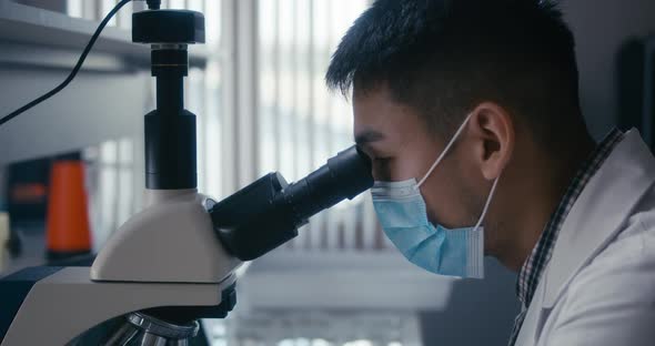 Scientist Studying Sample in Microscope