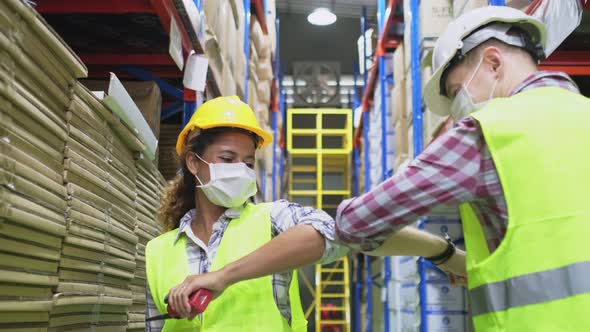 Industrial workers in warehouse factory have a greeting by touching the elbow or elbow bump.