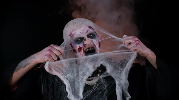 Scary Wounded Zombie Undead Guy Making Faces Hiding Through Spider Web Smiles Terribly Scares