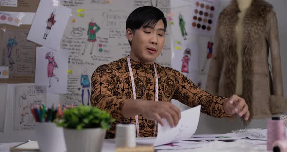 Fashion designer man showing a sketch of clothing