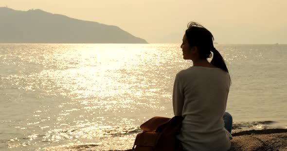 Woman looking at the sea under sunset