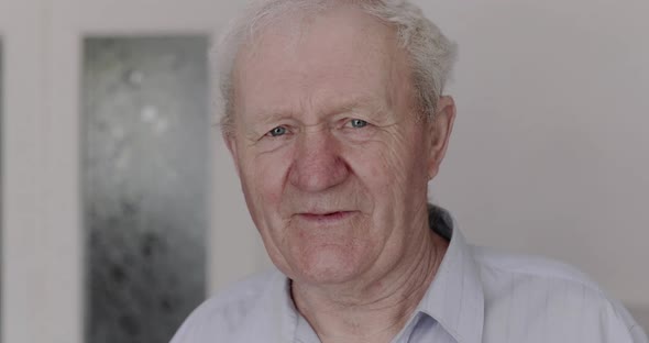 Handsome Senior Man Smiling and Talking Reassuringly at Camera and Indoor