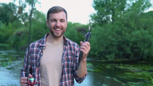 Fisherman Holds the Trout Caught in the River