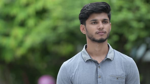 Young Happy Bearded Indian Man Smiling While Thinking Outdoors