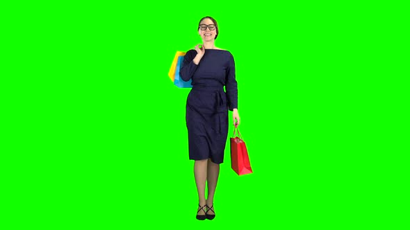 Girl with Packages in Her Hands Is Walking Along the Street. Green Screen