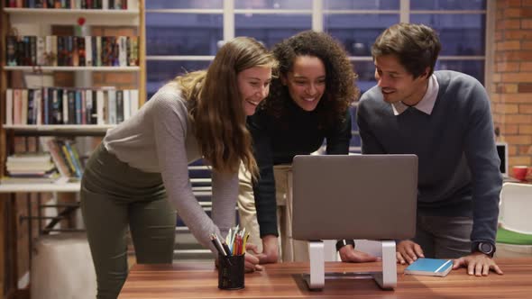 Creative businesspeople discussing over laptop in modern office