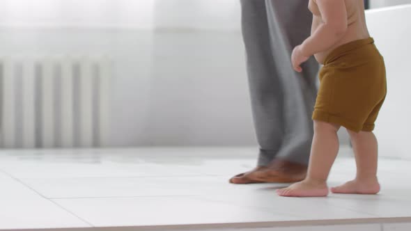 Unrecognizable Father and Toddler Walking Barefoot