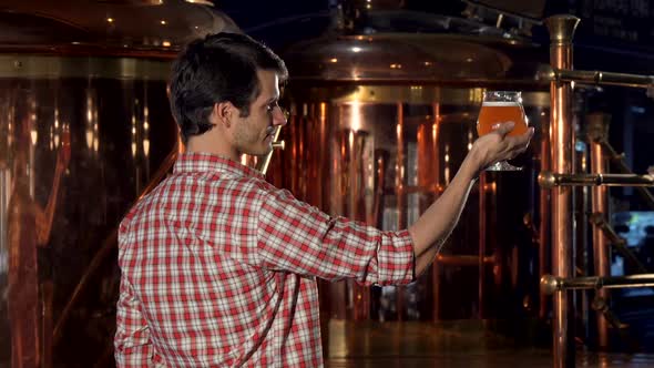 Rear View Shot of a Happy Brewer Showing Thumbs Up After Examining Beer